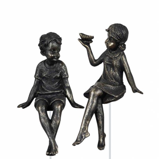 Brun pojke och flicka sittandes på en metallpinne