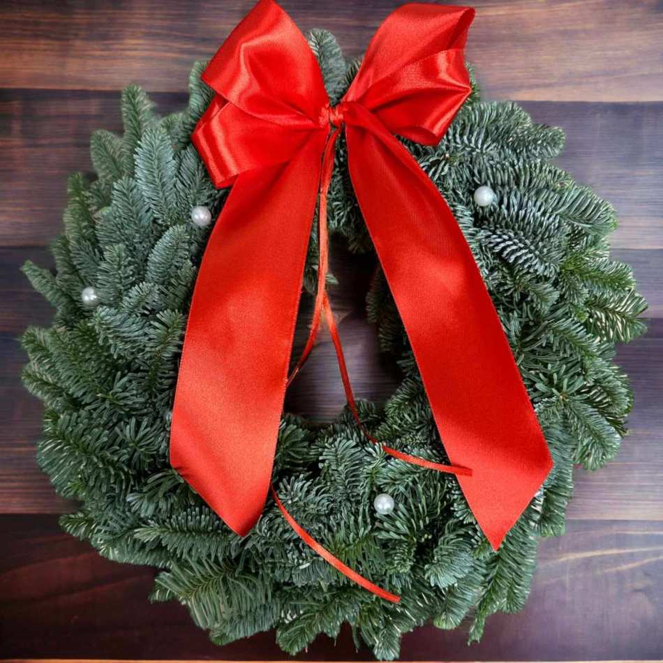 Krans med vita pärlor och röd rosett