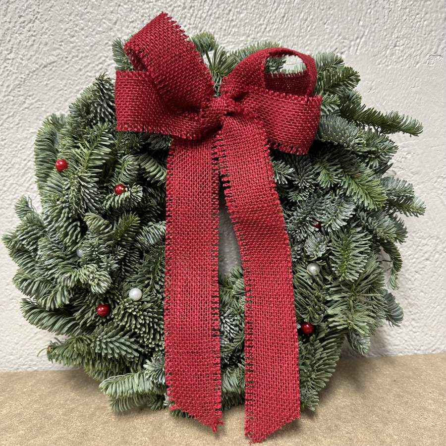 Julkrans med rosett av röd juteväv och pärlnålar. Diameter ca 30cm