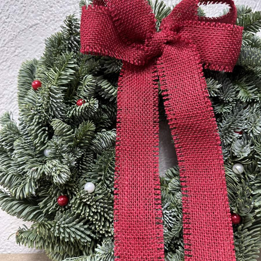 Julkrans med rosett av röd juteväv och pärlnålar. Diameter ca 30cm